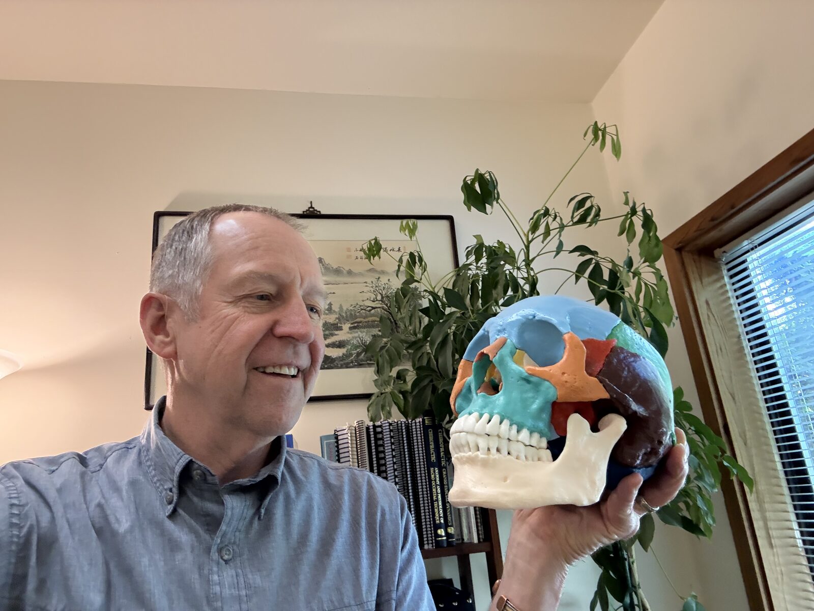 Dr. Mark William Cochran in his office holding an anatomical cranial model